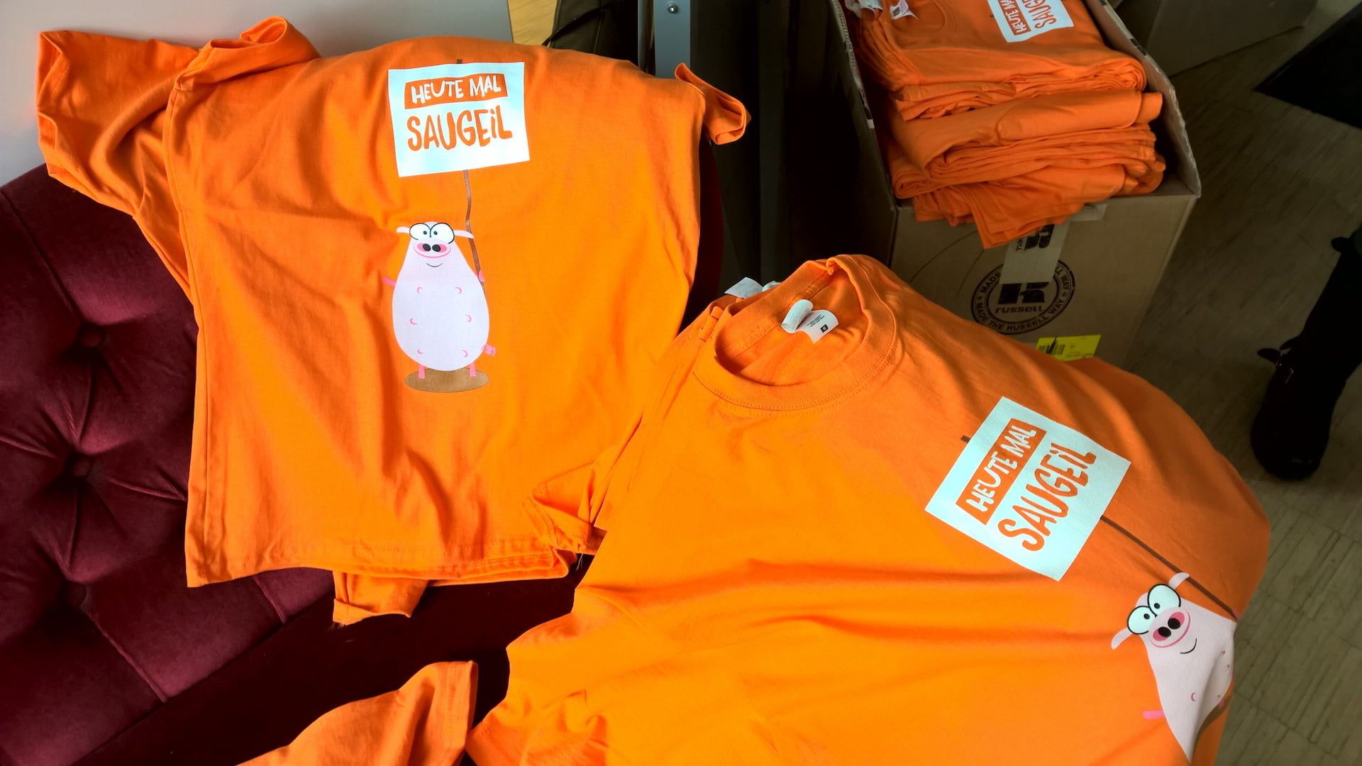 Ein oranges T-Shirt mit einem niedlichen Schweine-Motiv auf der Vorderseite.